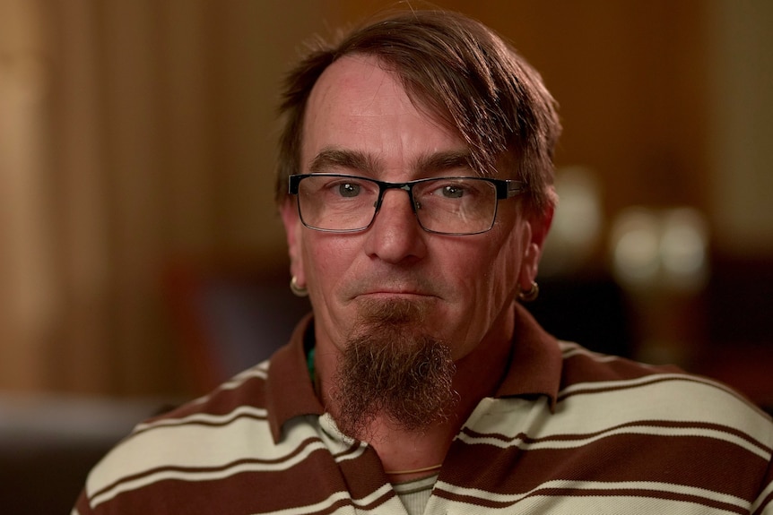 A man with brown hair, glasses and a goatee wearing a polo shirt.