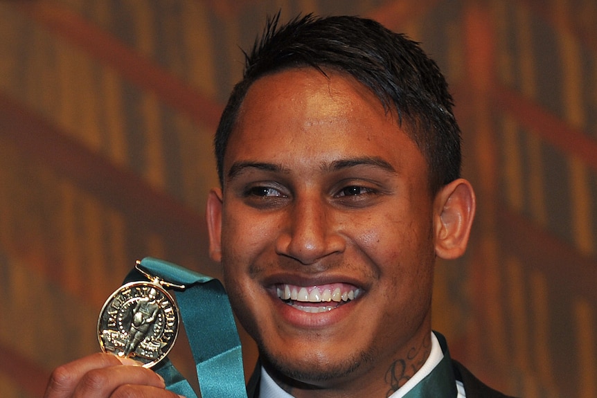 Ben Barba smiles while holding up the Dally M Medal hanging around his neck.