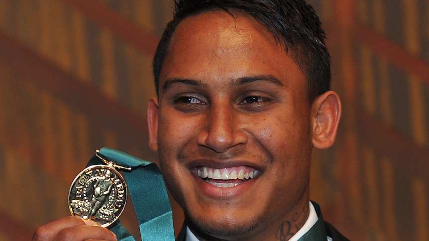 Ben Barba smiles while holding up the Dally M Medal hanging around his neck.