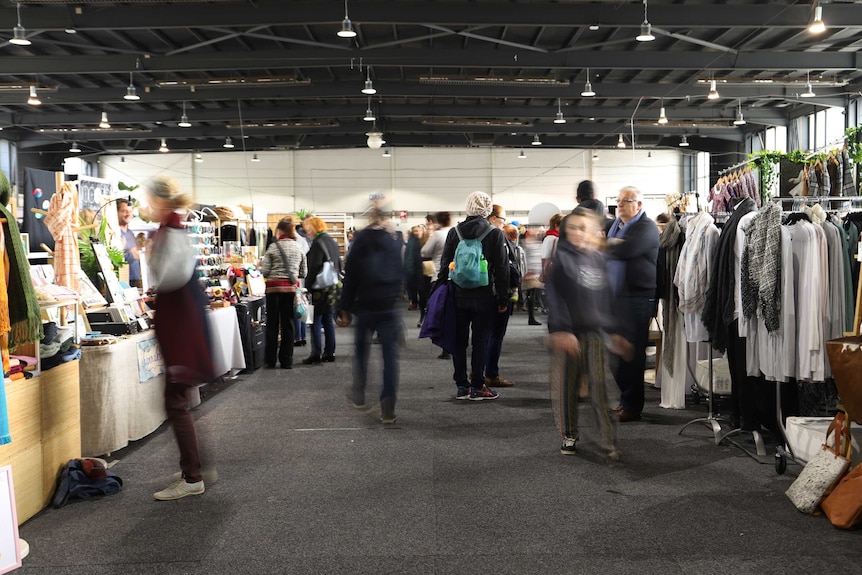 People walk around the Handmade market stalls in a big pavilion.