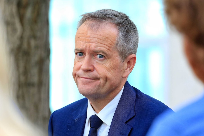 Bill Shorten, wearing a royal blue suit, half-smiles as he looks beyond the camera.