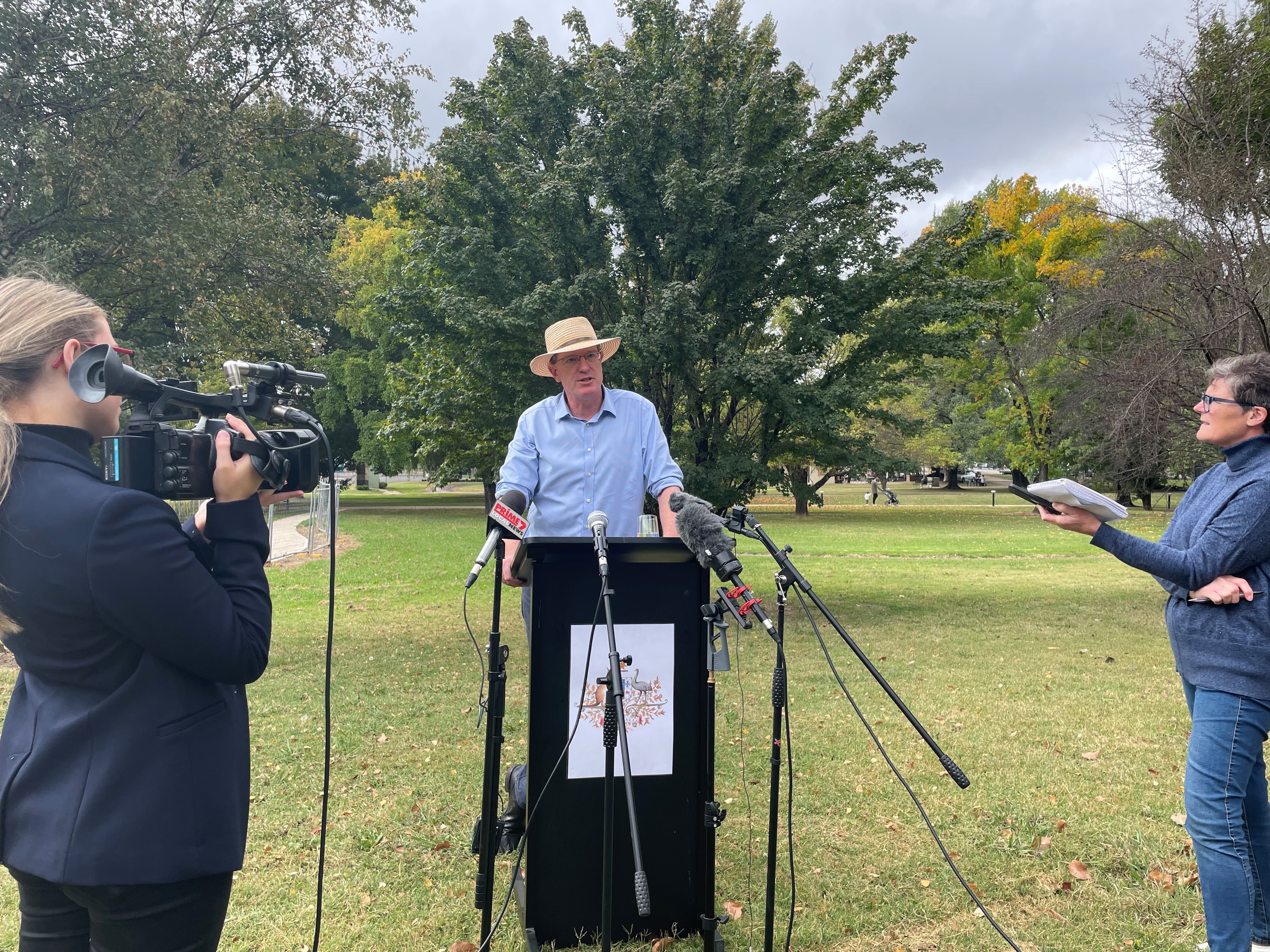 A man in a hat stands at a lectern