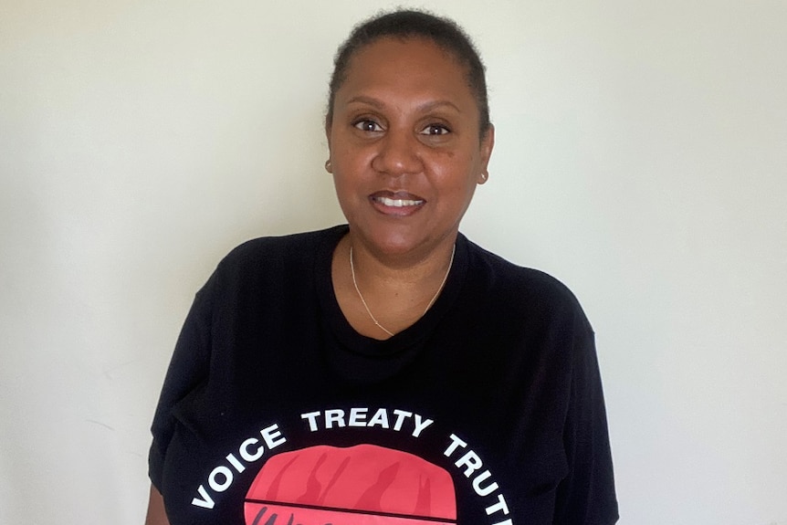A South Sea Islander woman wearing a black t-shirt that reads "voice treaty truth".