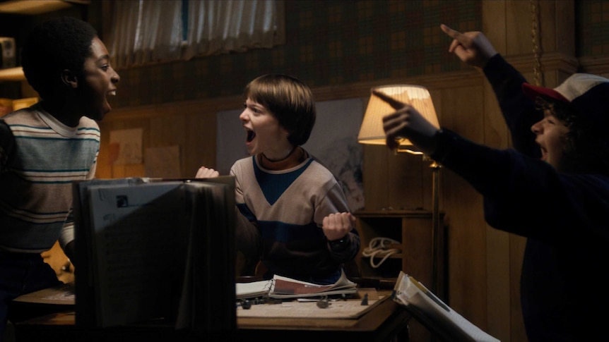 A scene in Stranger Things with three young 80s boys playing Dungeons & Dragons passionately