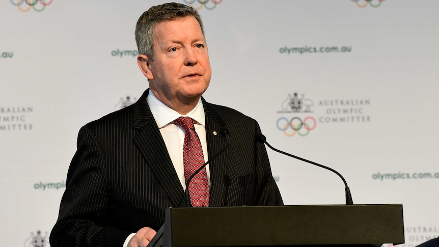 A sports executive stands at a lectern during an annual general meeting.