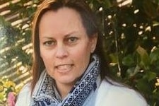 Sarah Anderson wears a floral scarf while standing in a garden.