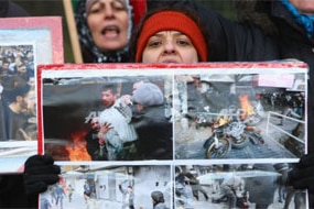Women hold photographs showing scenes from recent violent, anti-government demonstrations in Tehran while protesting outside ...