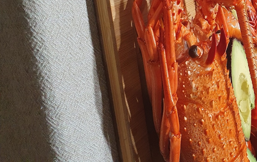 A plate of two Australian lobsters and plenty of prawns and oysters on a table.