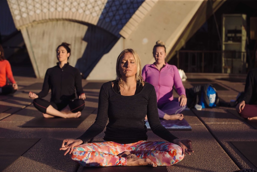 Sydneysiders practising yoga outside of the Sydney Opera House.