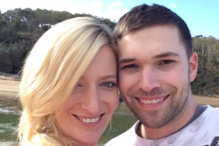 A man and woman smile for a photo at the beach