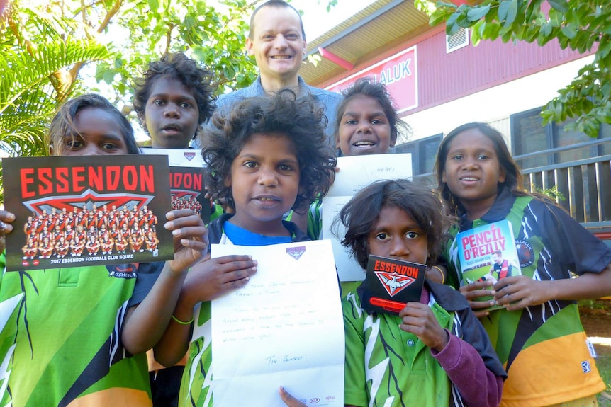 A group of Aboriginal children show off the books and stationary they were sent from the Essendon Football Club.