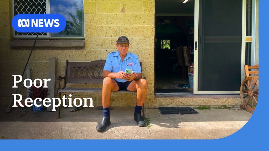 Poor reception. Man sitting on a bench outside a house looking at a mobile phone. 