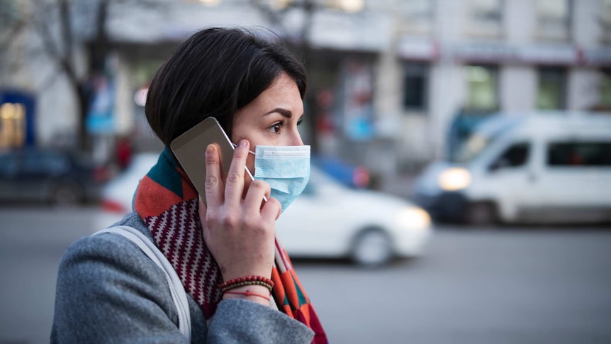 Young woman wearing face mask on phone.