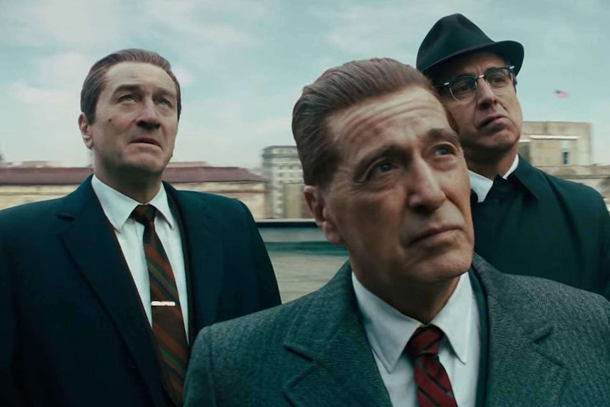 Robert De Niro, Al Pacino and Ray Romano dressed in suits, looking up.
