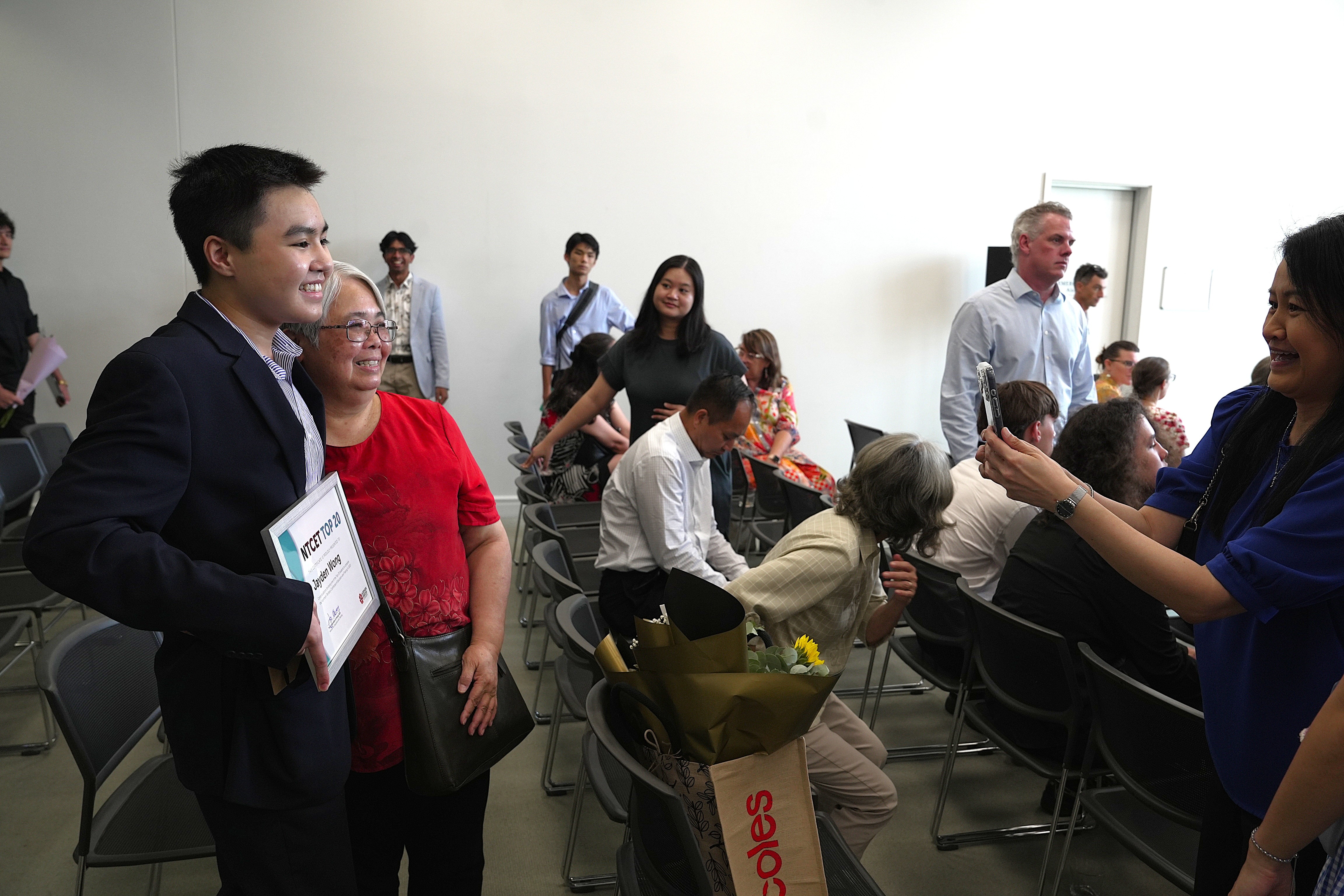 Un estudiante con un certificado posa para una foto con una mujer mayor.