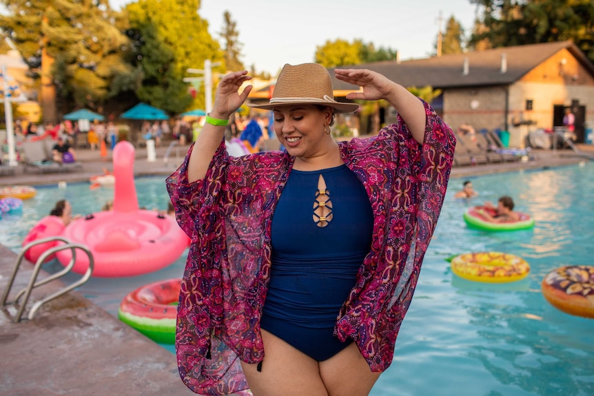 A woman wearing a hat, bathers and a bright coloured wrap
