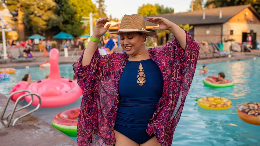 A woman wearing a hat, bathers and a bright coloured wrap