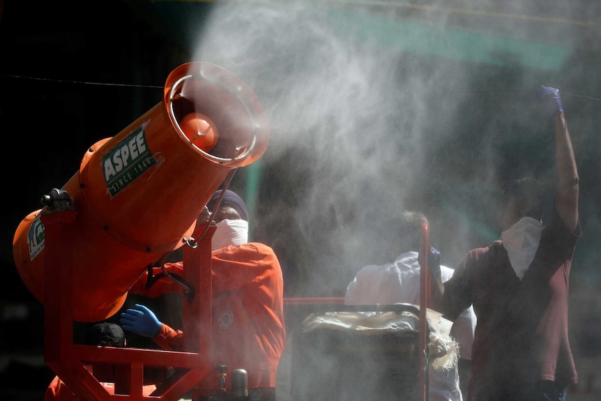 A worker uses a blower to decontaminate a street.