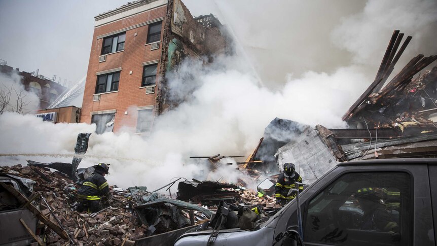 Firefighters work to extinguish a blaze at the scene of an explosion in East Harlem