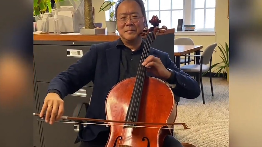A man wearing glasses playing the cello