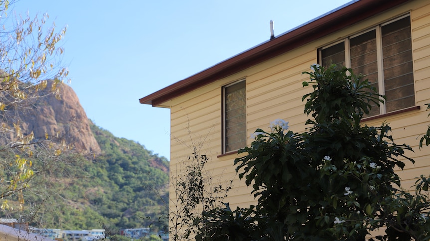 The side of a house with the view of a mountain, Castle Hill, in the background.