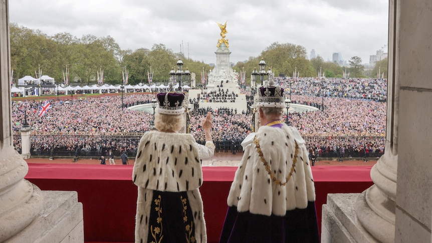 King Charles and Camilla wave to a crowd of thousands gathered in front of buckingham palace.