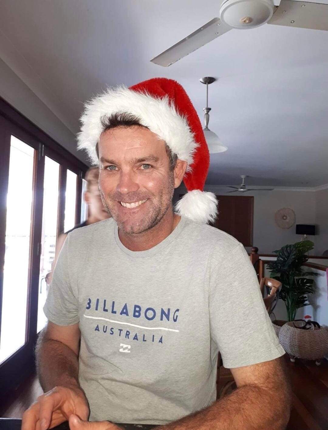 A man grinning wearing a Santa hat
