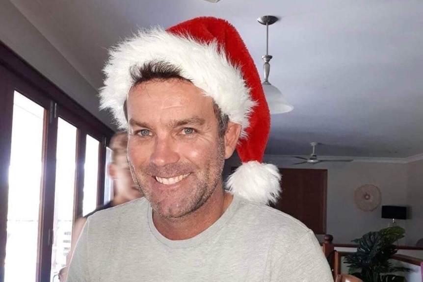 A man grinning wearing a Santa hat