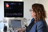 A doctor looks at a screen that shows images of scarring on hearts