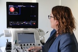 A doctor looks at a screen that shows images of scarring on hearts