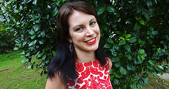 A woman in a red and white dress stands in a backyard.