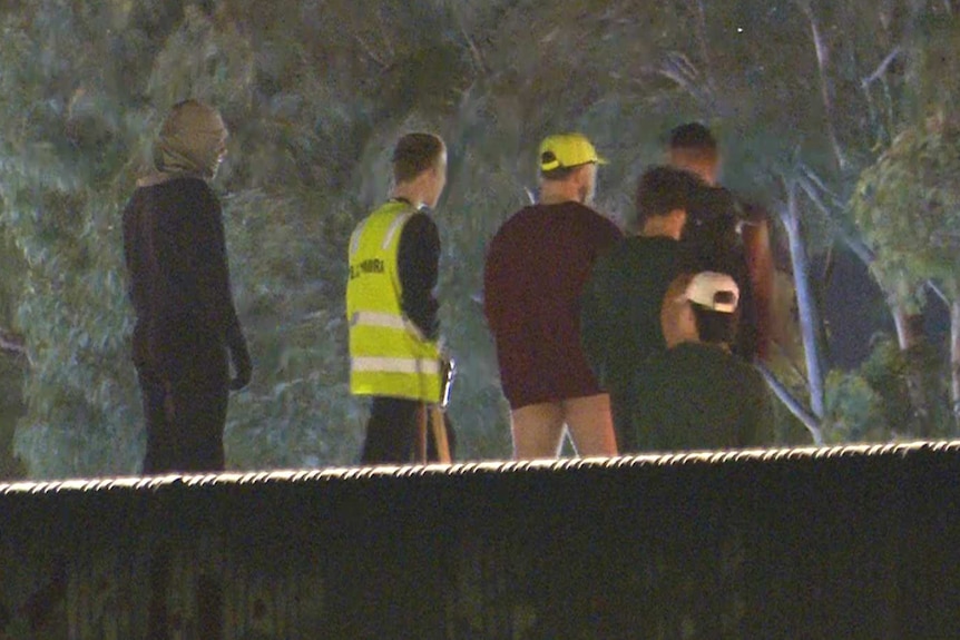 several teenagers standing on a roof in the night