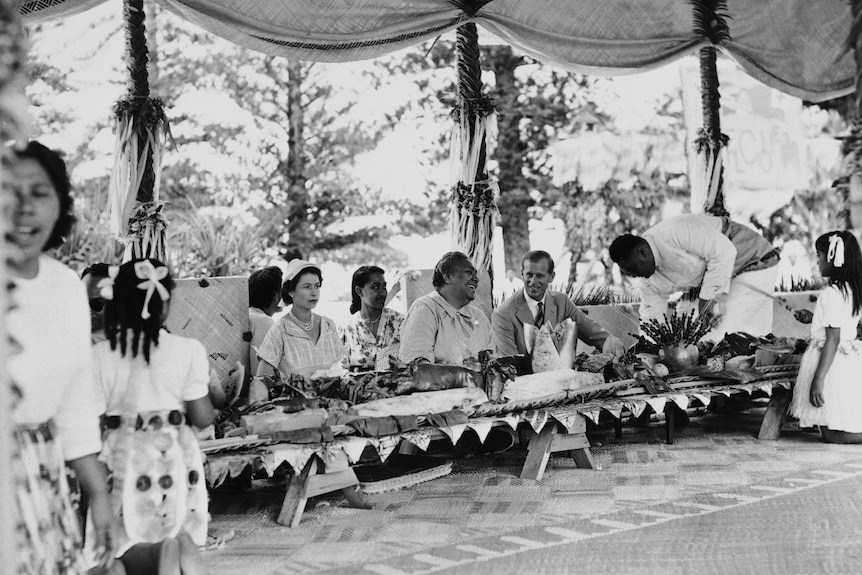 the queen looks formally ahead at a traditional, low table beside queen salote of tonga 
