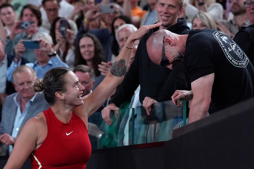 Aryna Sabalenka pats the head of her fitness coach after her Australian Open win.