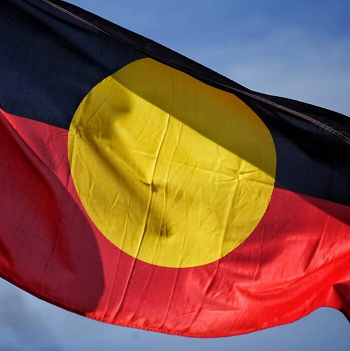 The Aboriginal flag flies against a blue sky.