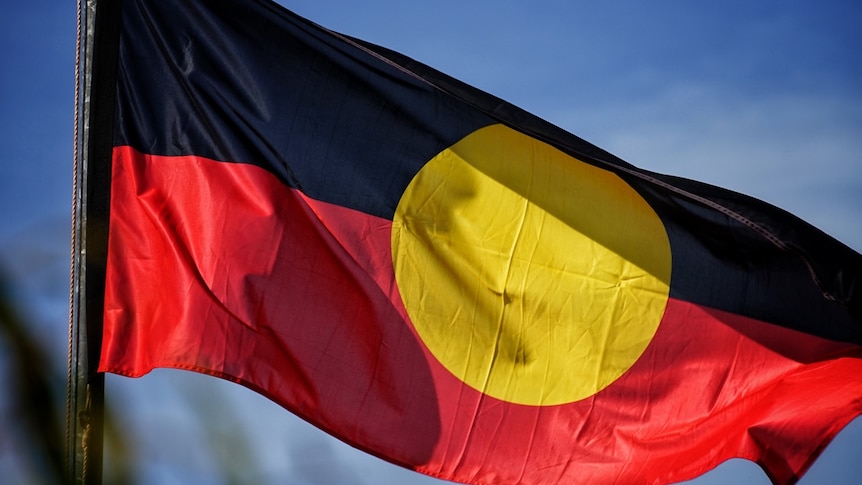 The Aboriginal flag flies against a blue sky.