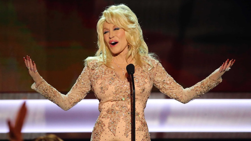 Dolly Parton on stage with arts outstretched