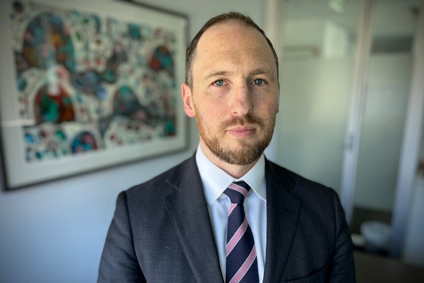 A man in a suit looking into the camera.