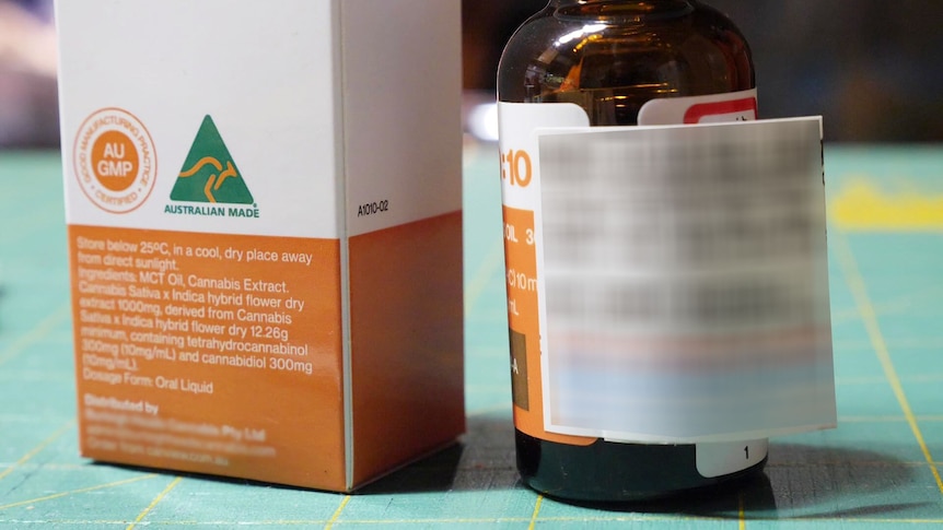 A cannabis oil bottle sits on a bench with the packaging next to it.