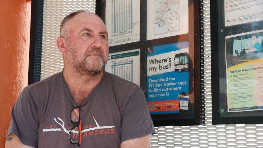 Man sitting at bus stop staring into the distance