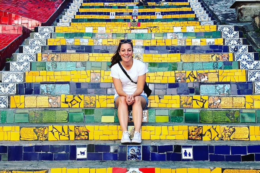 Jessica Shapland sits on some colour stairs to depict taking an adult gap year.