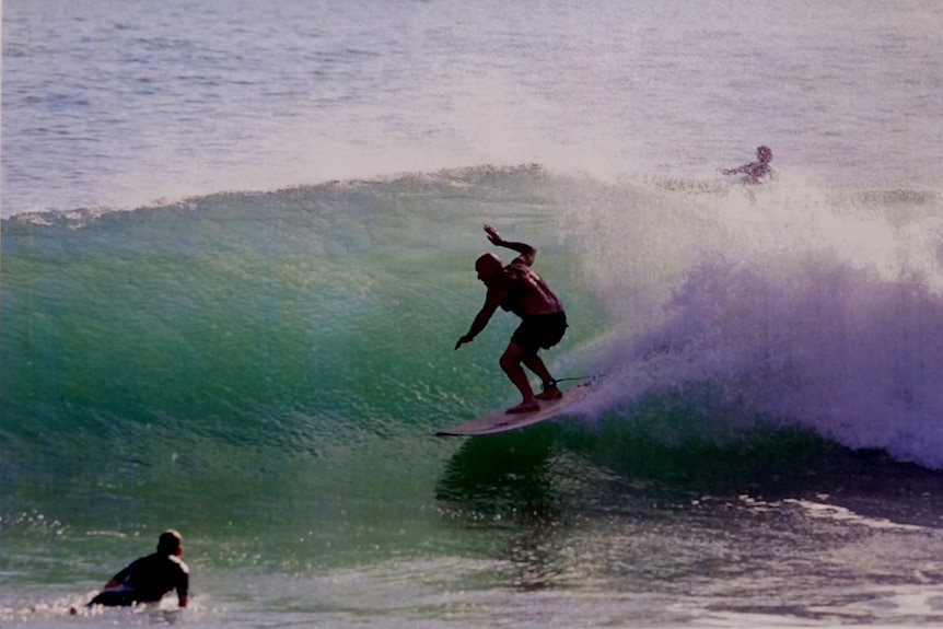 A man rides a wave on a surfboard