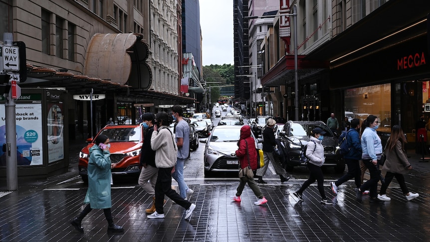 People wearing face masks cross a busy intersection in Sydney's CBD.