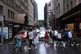 People wearing face masks cross a busy intersection in Sydney's CBD.