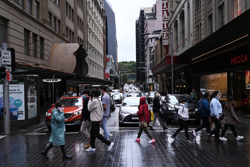 People wearing face masks cross a busy intersection in Sydney's CBD.