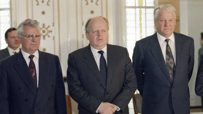 Leonid Kravchuk, Stanislav Shushkevich and Boris Yeltsin standing in a row behind a desk