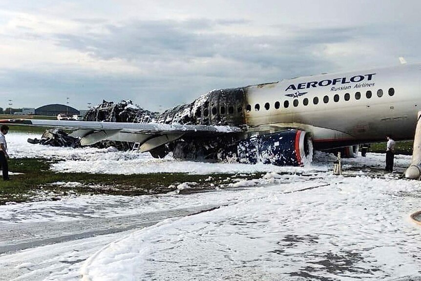 A collapsed and blacked half of the plane is covered in white foam that looks like snow.