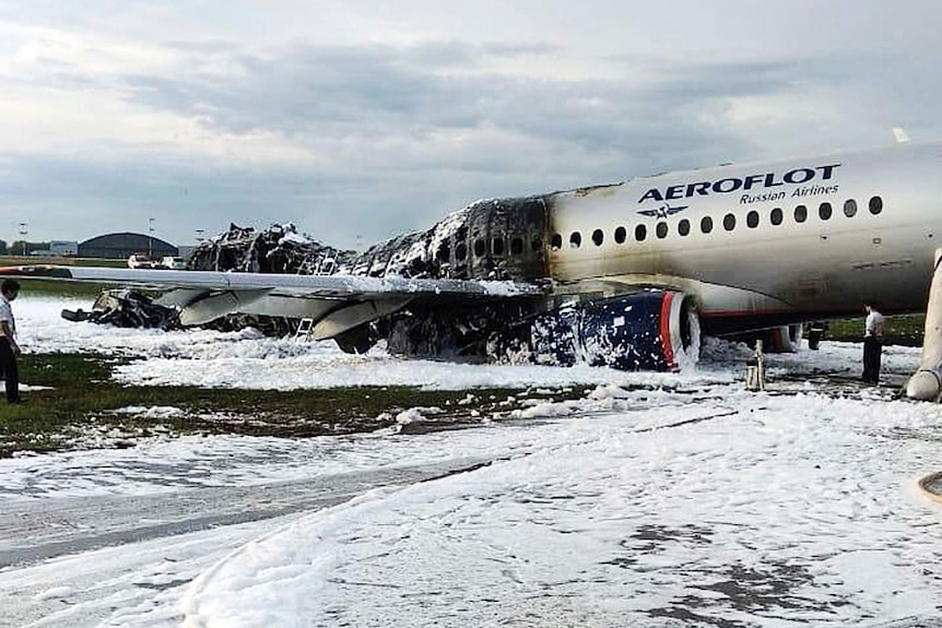 A collapsed and blacked half of the plane is covered in white foam that looks like snow.