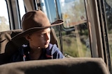 A young student looks out the window of a school bus