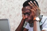 Man with head in hands looking confused at laptop for a story about understanding work payslips.